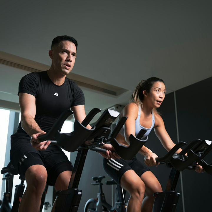 man and woman on indoor cycles, spinning class at pure fitness studio, spin class hong kong